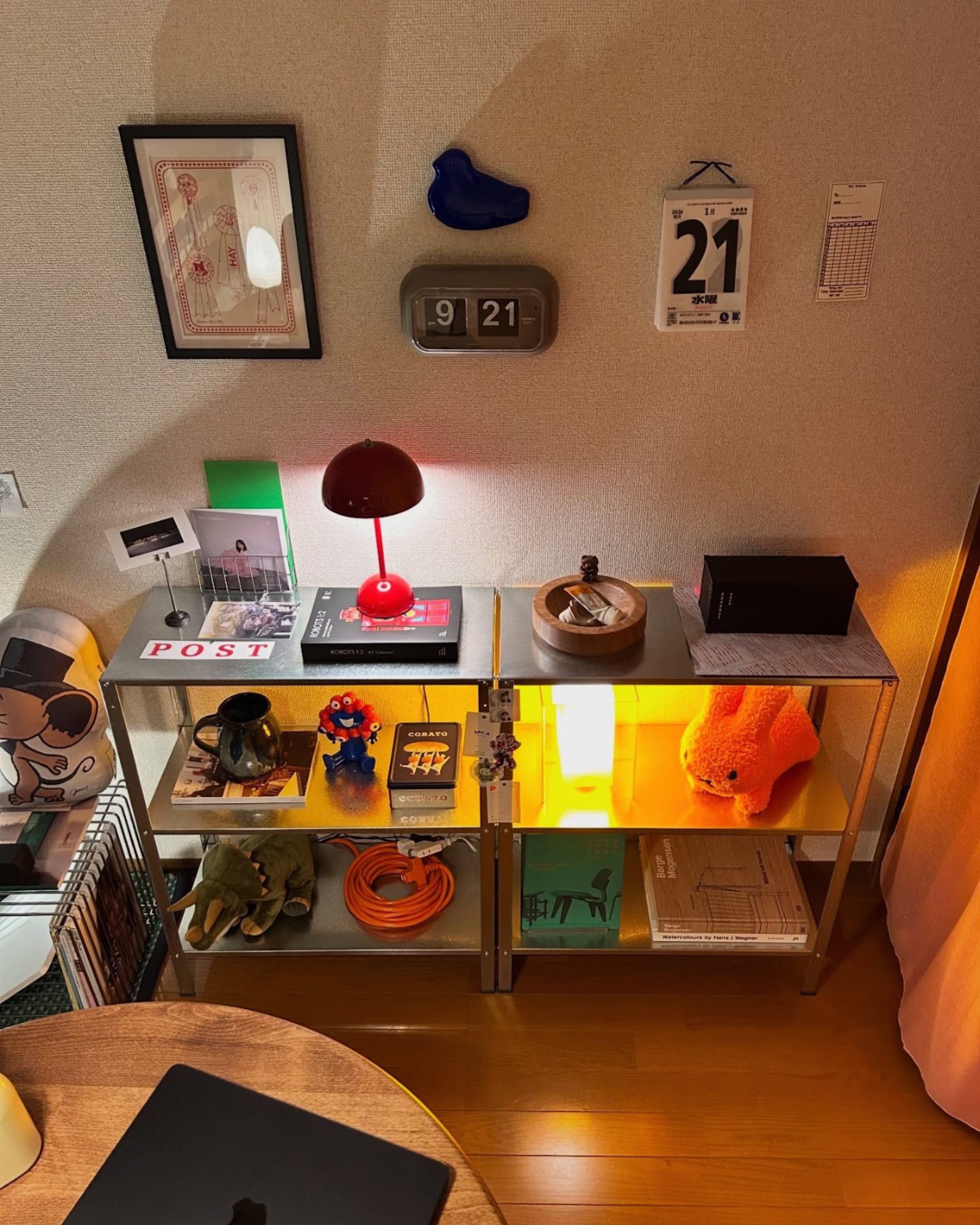 Red mushroom designer table lamp glowing on a retro shelving unit — playful warm-lit collector interior