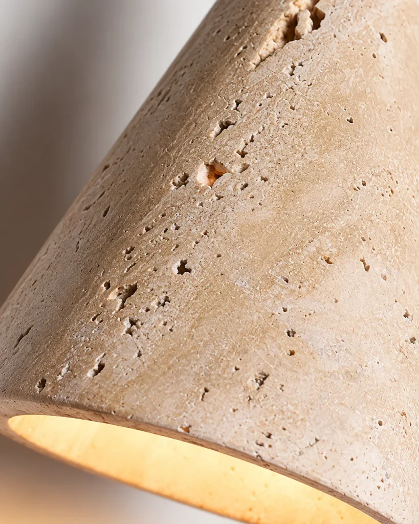 Applique POLI, cono in travertino sospeso con sfera in noce – dettaglio dei pori sul bordo illuminato del paralume
